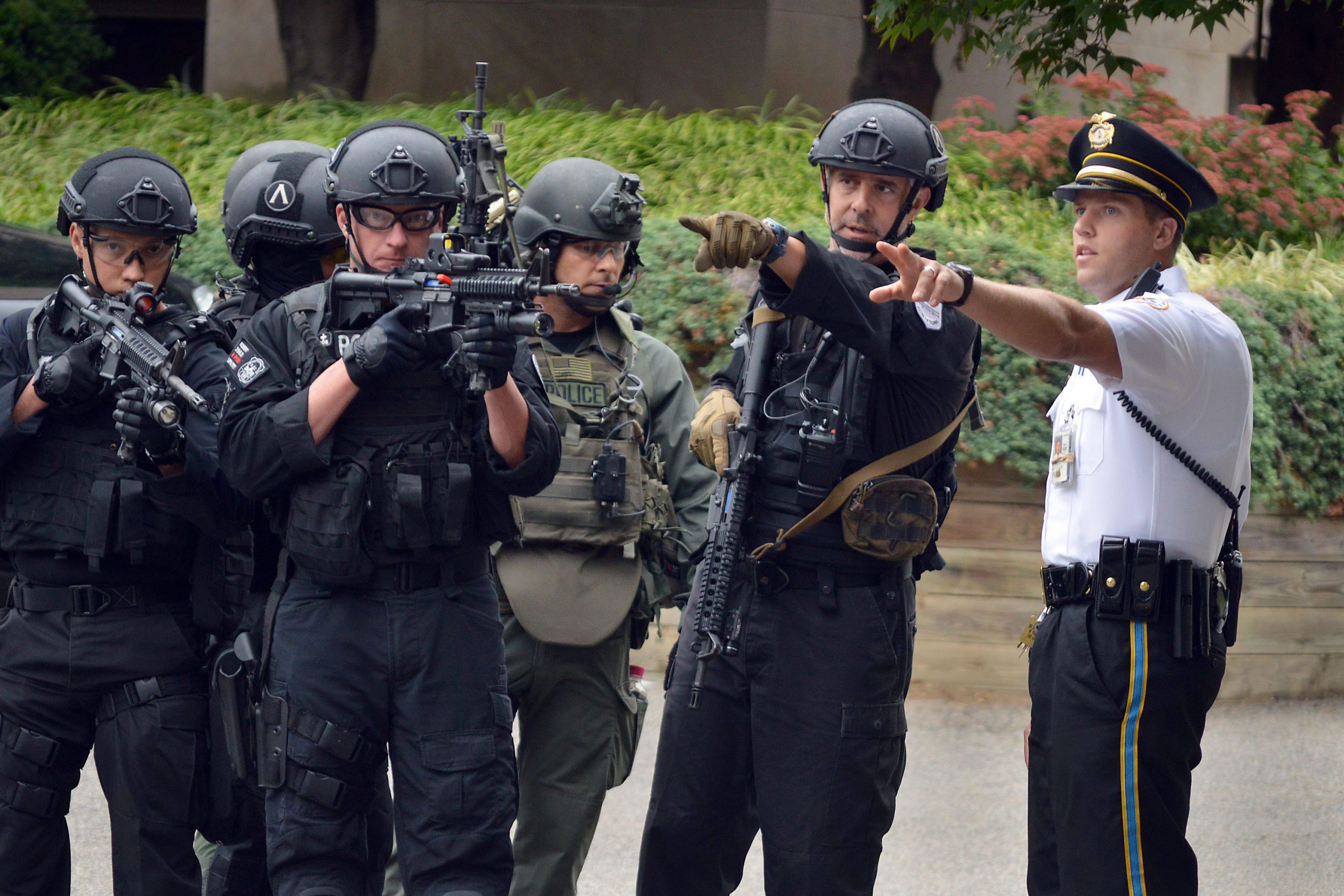 Security Officers with weapons standing outside of building and pointing