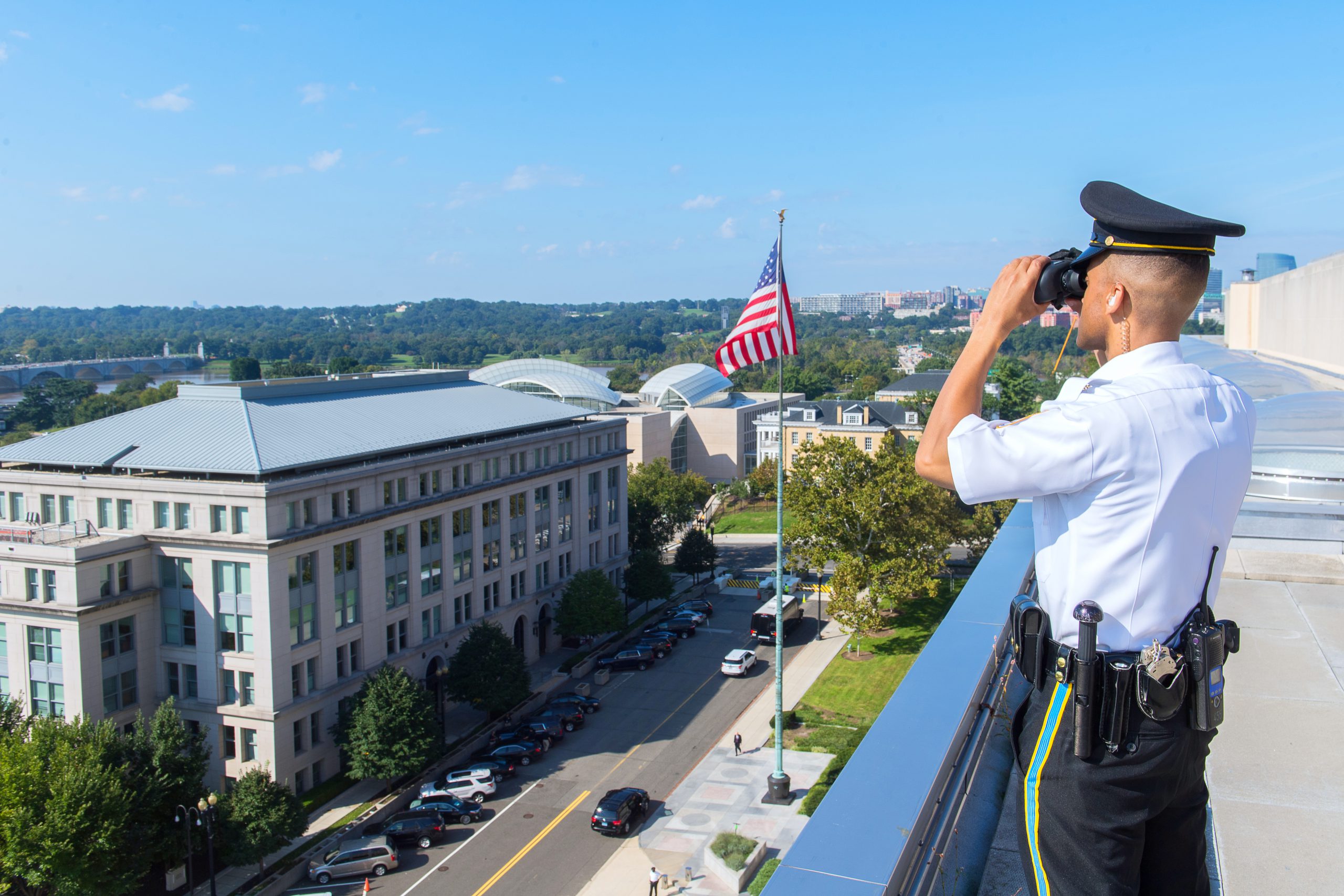 Security Officer looking through binoculars on top of building